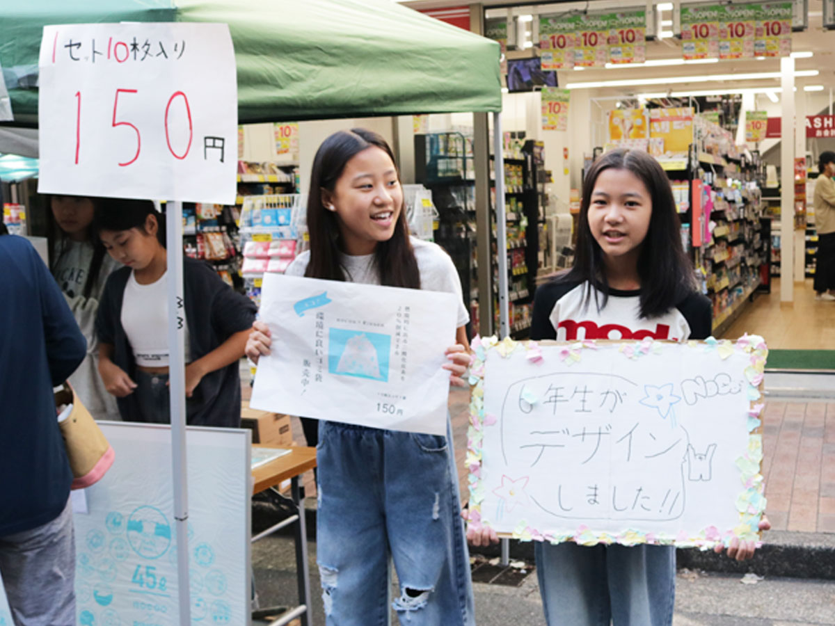 POPや看板を持って呼び込みする児童たち